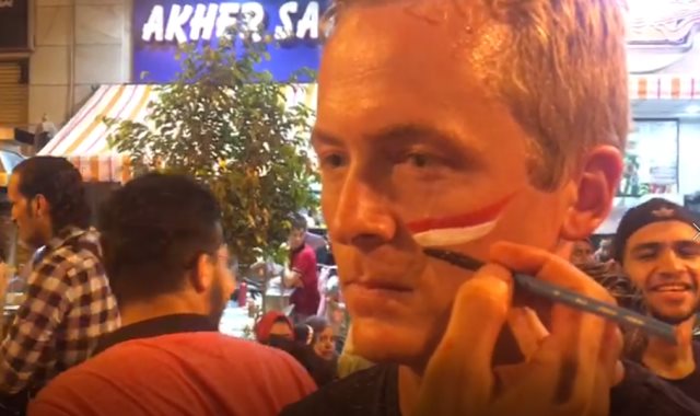 أحد الأجانب يرسم علم مصر على وجهه