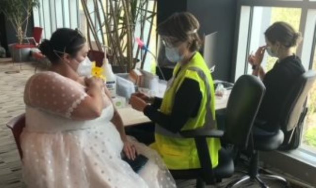 العروس خلال تلقي اللقاح بفستان زفافها