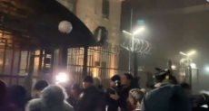 أشخاص يلقون السفارة الروسية بكييف بقنابل دخان