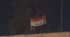 متظاهر يرفع العلم العراقى على أسوار القنصلية الإيرانية